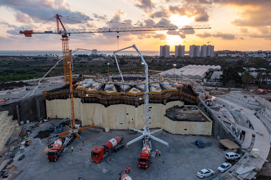 The sun sets on Sunday evening with work fully under way to cast the roof structure. The base of the east berm is used as a staging area for two of the concrete pumps.